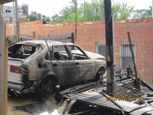 Charred car below the telephone pole.